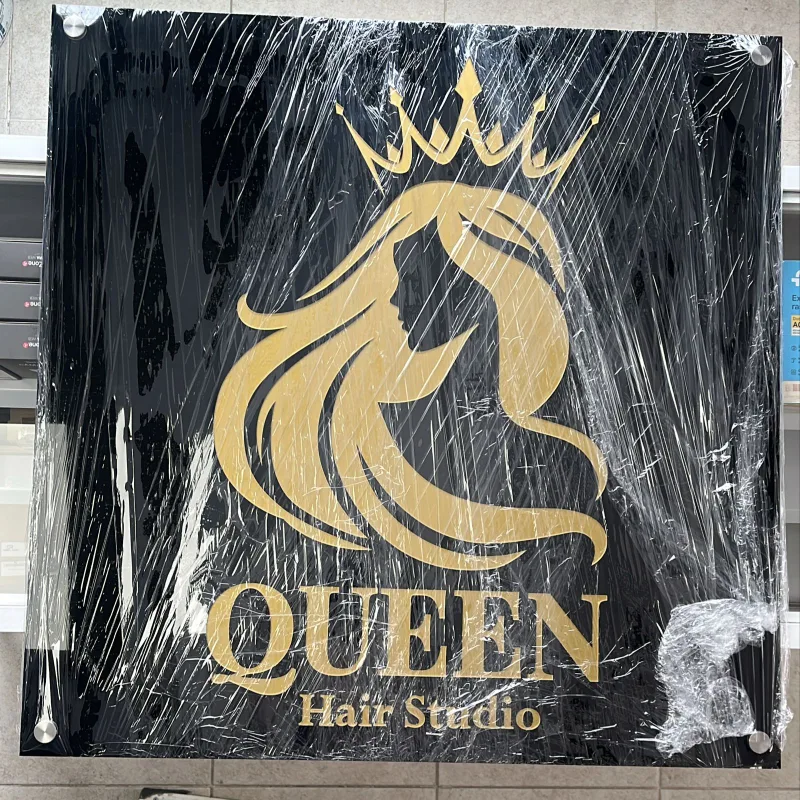 Letrero de identidad comercial con logotipo dorado sobre acrílico y vinil